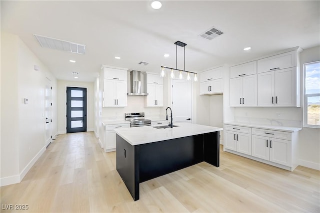 2461 S Blagg Rd, Pahrump, NV 89048 - kitchen with stainless steel range with electric cooktop, wall chimney range hood, light wood-type flooring, light countertops, and white cabinetry