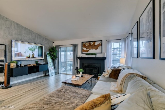 640 Thornewood Pl, Las Vegas, NV 89123 - living area with healthy amount of natural light, wood finished floors, vaulted ceiling, and a glass covered fireplace