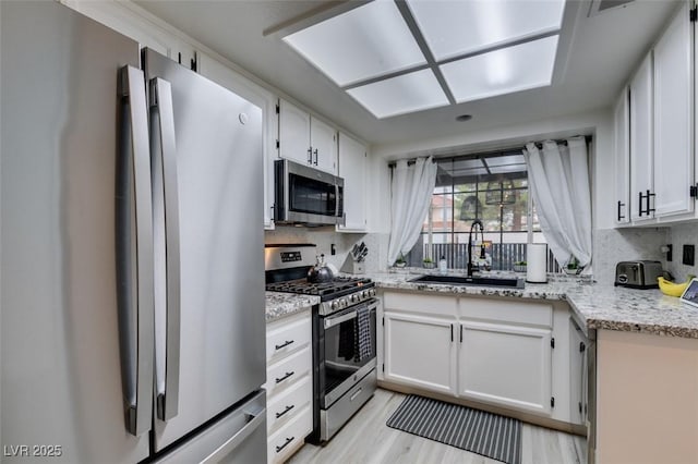 640 Thornewood Pl, Las Vegas, NV 89123 - kitchen with appliances with stainless steel finishes, tasteful backsplash, light wood finished floors, and white cabinets