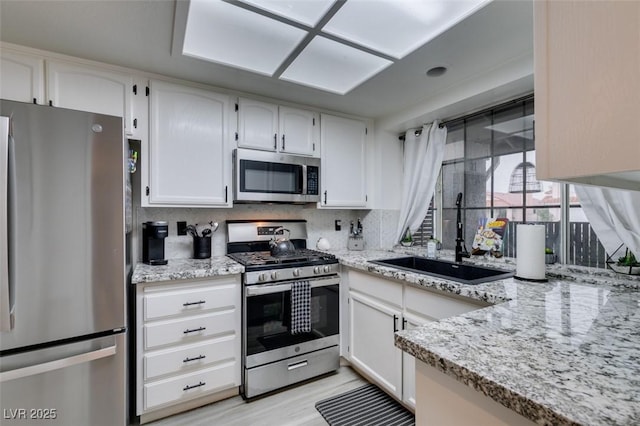 640 Thornewood Pl, Las Vegas, NV 89123 - kitchen with appliances with stainless steel finishes, white cabinetry, light stone counters, light wood-style floors, and tasteful backsplash