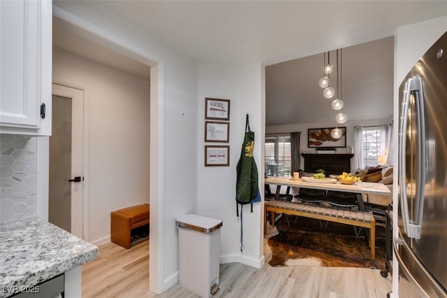 640 Thornewood Pl, Las Vegas, NV 89123 - kitchen with stainless steel refrigerator, light wood-type flooring, white cabinetry, light stone counters, and pendant lighting