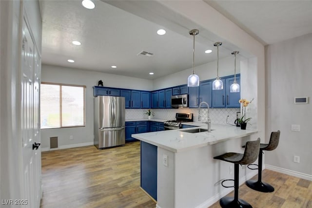 2766 Mintlaw Ave, Henderson, NV 89044 - kitchen featuring stainless steel appliances, blue cabinetry, a peninsula, light wood-type flooring, and tasteful backsplash
