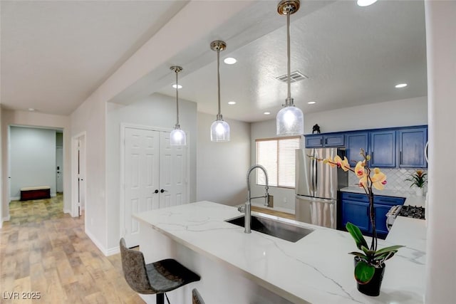 2766 Mintlaw Ave, Henderson, NV 89044 - kitchen with freestanding refrigerator, blue cabinets, light wood-style flooring, recessed lighting, and light stone countertops