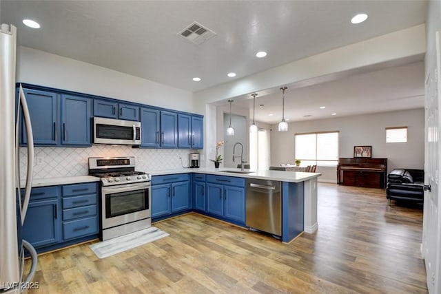 2766 Mintlaw Ave, Henderson, NV 89044 - kitchen with stainless steel appliances, blue cabinets, a peninsula, light countertops, and decorative backsplash