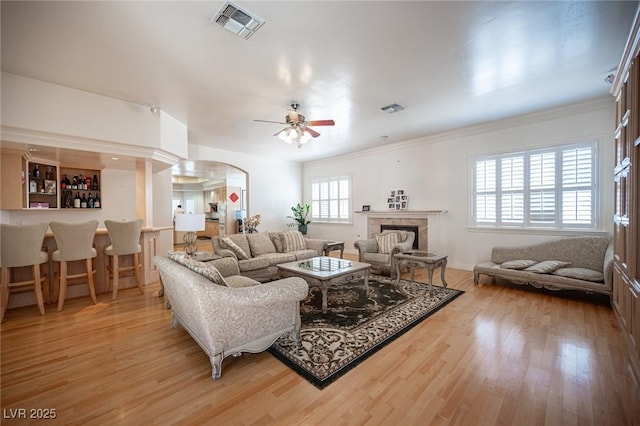 8925 Wild Creek Ct, Las Vegas, NV 89117 - living area with light wood-style floors, ceiling fan, a tile fireplace, arched walkways, and ornamental molding