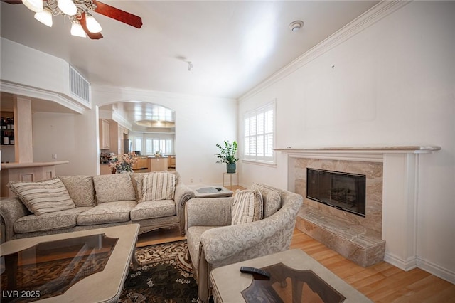 8925 Wild Creek Ct, Las Vegas, NV 89117 - living room with ceiling fan, light wood finished floors, a premium fireplace, ornamental molding, and arched walkways
