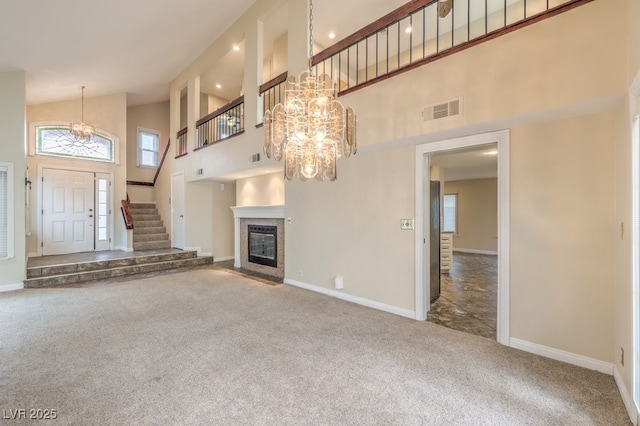 56 Westheimer Rd, Henderson, NV 89074 - unfurnished living room featuring a chandelier, high vaulted ceiling, carpet floors, stairway, and a fireplace with flush hearth