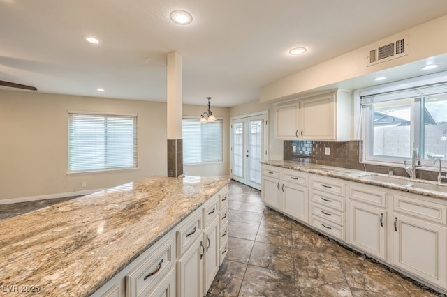 56 Westheimer Rd, Henderson, NV 89074 - kitchen with white cabinetry, plenty of natural light, backsplash, light stone counters, and recessed lighting