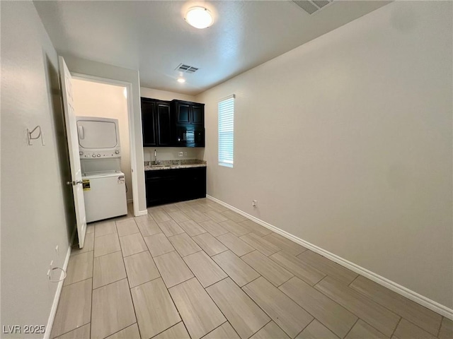 4117 Midnight Crest Ave, North Las Vegas, NV 89031 - kitchen with dark cabinetry, stacked washer and clothes dryer, and light countertops
