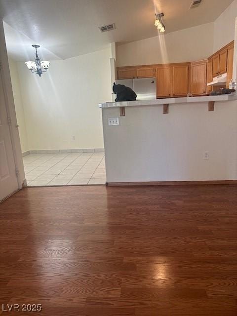 2110 Los Feliz St Unit 2091, Las Vegas, NV 89156 - kitchen with refrigerator, light wood-style floors, a kitchen breakfast bar, a chandelier, and a peninsula