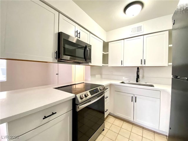4980 Apollostar Ct, Las Vegas, NV 89115 - kitchen featuring appliances with stainless steel finishes, open shelves, light countertops, white cabinetry, and light tile patterned floors