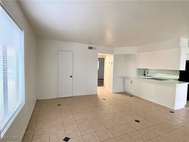 4980 Apollostar Ct, Las Vegas, NV 89115 - kitchen featuring light countertops, white cabinetry, light tile patterned flooring, a peninsula, and fridge