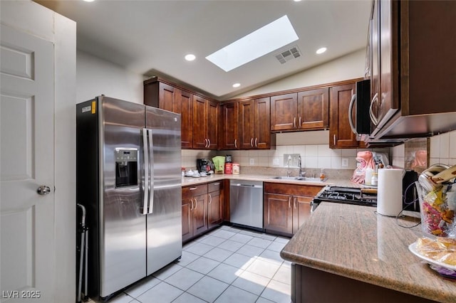 1949 King Hill St, Las Vegas, NV 89106 - kitchen with stainless steel appliances, a skylight, lofted ceiling, light tile patterned flooring, and decorative backsplash