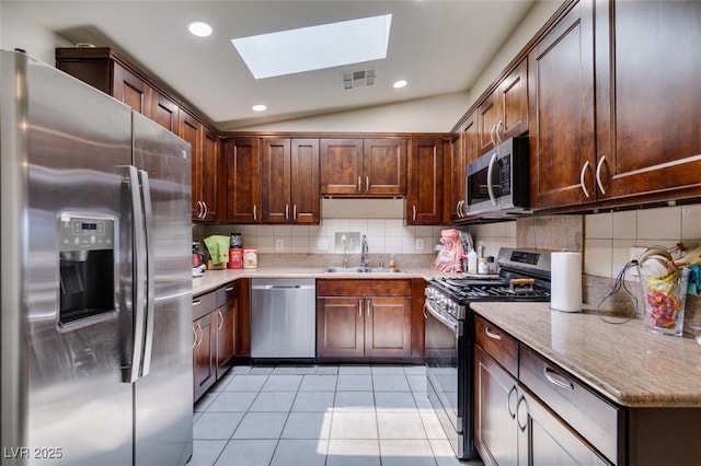 1949 King Hill St, Las Vegas, NV 89106 - kitchen with appliances with stainless steel finishes, a skylight, tasteful backsplash, light tile patterned flooring, and lofted ceiling