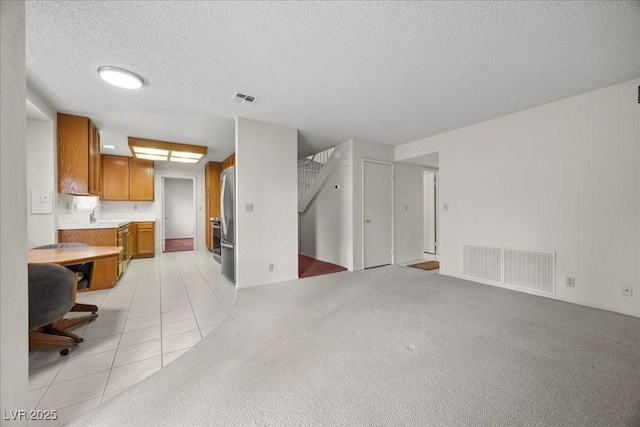 2344 Valleywood St, Henderson, NV 89014 - kitchen with light countertops, brown cabinetry, a textured ceiling, appliances with stainless steel finishes, and open floor plan