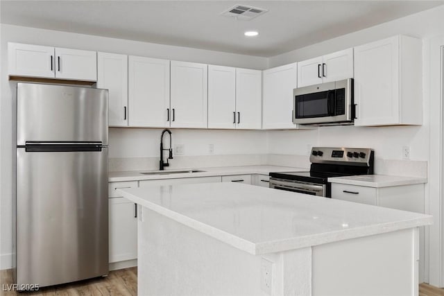 732 N 9th St, Las Vegas, NV 89101 - kitchen with stainless steel appliances, light wood-type flooring, white cabinetry, a center island, and recessed lighting