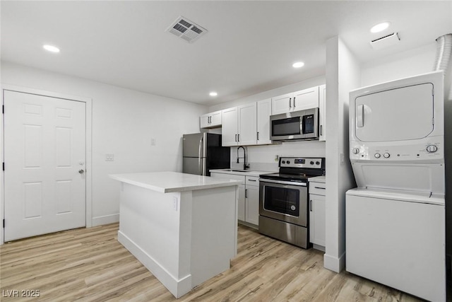 732 N 9th St, Las Vegas, NV 89101 - kitchen with stainless steel appliances, stacked washing machine and dryer, light wood-type flooring, white cabinetry, and recessed lighting