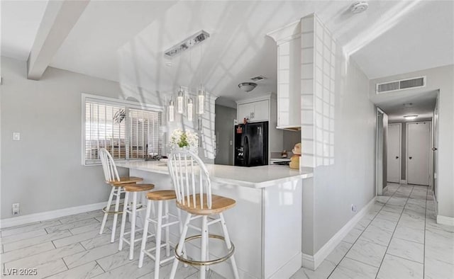 824 Salem Dr, Las Vegas, NV 89107 - kitchen featuring black fridge, light marble finish floors, white cabinetry, a breakfast bar area, and beam ceiling
