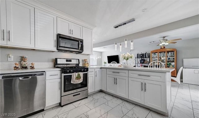 824 Salem Dr, Las Vegas, NV 89107 - kitchen with appliances with stainless steel finishes, a peninsula, light marble finish flooring, and light countertops