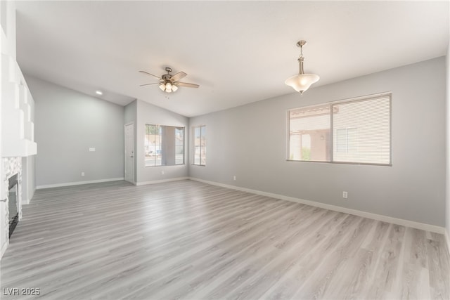 5524 Cleary Ct, Las Vegas, NV 89108 - unfurnished living room with ceiling fan, vaulted ceiling, light wood-type flooring, and a stone fireplace