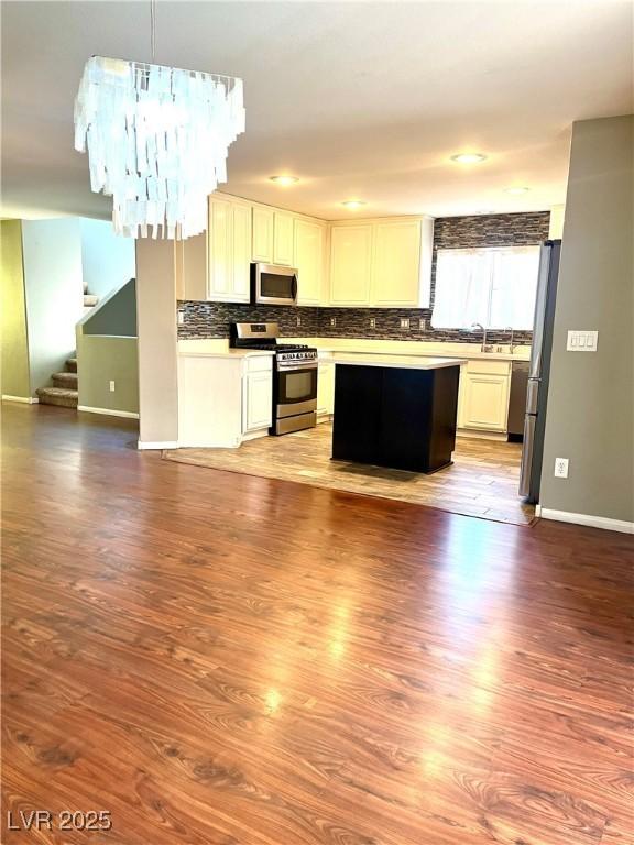 10450 Badger Ravine St, Las Vegas, NV 89178 - kitchen featuring stainless steel appliances, open floor plan, tasteful backsplash, wood finished floors, and a center island