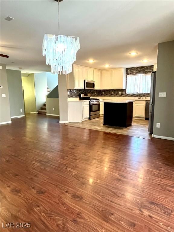 10450 Badger Ravine St, Las Vegas, NV 89178 - kitchen featuring appliances with stainless steel finishes, open floor plan, tasteful backsplash, dark wood-style floors, and pendant lighting
