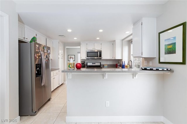 9836 Russett Wood Cir, Las Vegas, NV 89117 - kitchen with appliances with stainless steel finishes, a peninsula, white cabinetry, light tile patterned floors, and recessed lighting
