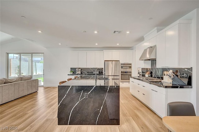 2670 Skylark Trail St, Henderson, NV 89044 - kitchen with extractor fan, stainless steel appliances, light wood finished floors, backsplash, and recessed lighting