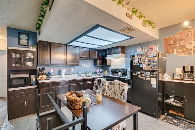 4300 N Lamont St Unit 275, Las Vegas, NV 89115 - kitchen with black appliances, a textured ceiling, under cabinet range hood, light tile patterned flooring, and dark brown cabinets