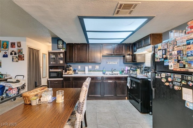 4300 N Lamont St Unit 275, Las Vegas, NV 89115 - kitchen with black appliances, under cabinet range hood, dark brown cabinetry, a textured ceiling, and light tile patterned floors