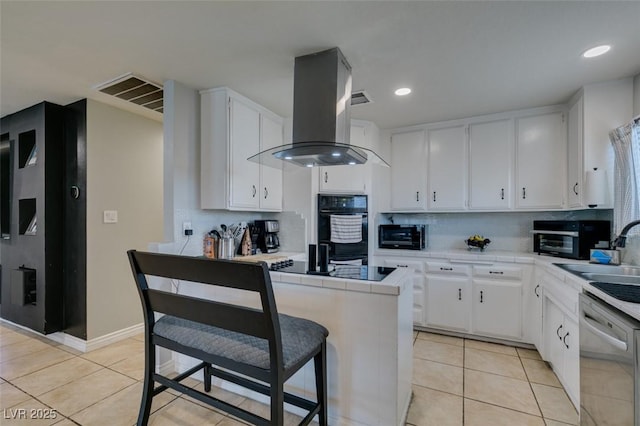 1705 Ivanhoe Way, Las Vegas, NV 89102 - kitchen with island exhaust hood, tile countertops, black appliances, light tile patterned floors, and recessed lighting