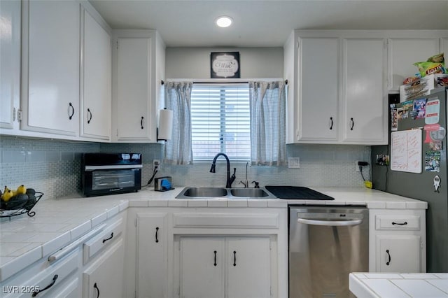 1705 Ivanhoe Way, Las Vegas, NV 89102 - kitchen featuring stainless steel dishwasher, white cabinetry, tasteful backsplash, tile counters, and freestanding refrigerator