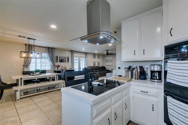 1705 Ivanhoe Way, Las Vegas, NV 89102 - kitchen featuring island exhaust hood, tile counters, black appliances, a peninsula, and white cabinets