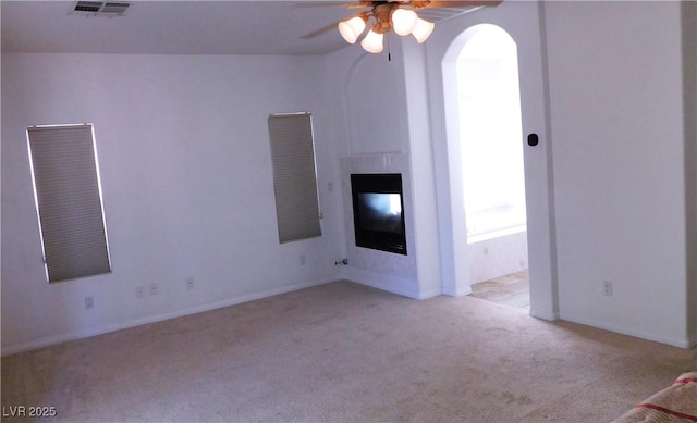 2587 Mizzoni Cir, Henderson, NV 89052 - unfurnished living room with carpet flooring, ceiling fan, a glass covered fireplace, and arched walkways