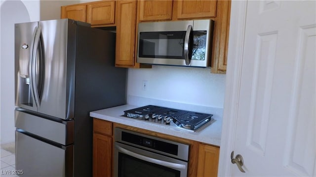 2587 Mizzoni Cir, Henderson, NV 89052 - kitchen featuring appliances with stainless steel finishes, light countertops, brown cabinets, and light tile patterned floors