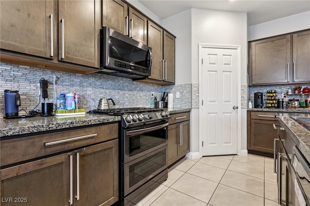 5246 Belmont Mill Ct, Las Vegas, NV 89122 - kitchen with appliances with stainless steel finishes, dark stone countertops, dark brown cabinetry, and light tile patterned floors