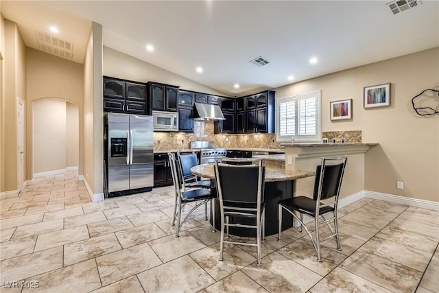 5681 Exotic Rosette Ave, Las Vegas, NV 89139 - kitchen with stainless steel appliances, arched walkways, exhaust hood, backsplash, and dark cabinetry