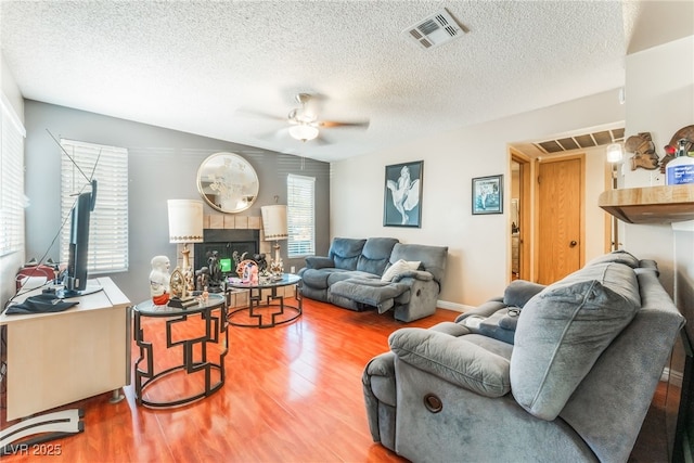 2666 Aarondavid Dr, Las Vegas, NV 89121 - living area with wood finished floors, a ceiling fan, a tiled fireplace, and a textured ceiling