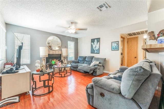 2666 Aarondavid Dr, Las Vegas, NV 89121 - living room featuring wood finished floors, ceiling fan, a textured ceiling, and a tile fireplace