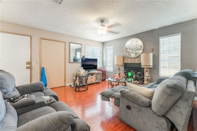 2666 Aarondavid Dr, Las Vegas, NV 89121 - living area featuring light wood finished floors, healthy amount of natural light, ceiling fan, a textured ceiling, and a fireplace