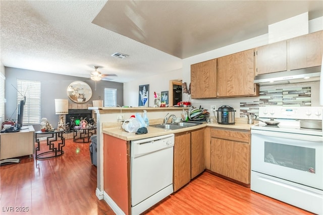2666 Aarondavid Dr, Las Vegas, NV 89121 - kitchen with white appliances, under cabinet range hood, light wood-style floors, a peninsula, and a textured ceiling