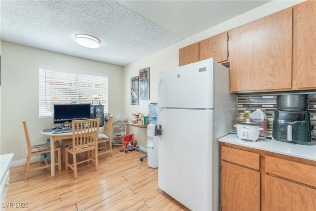 2666 Aarondavid Dr, Las Vegas, NV 89121 - kitchen featuring freestanding refrigerator, light wood-style floors, light countertops, tasteful backsplash, and a textured ceiling