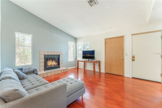2666 Aarondavid Dr, Las Vegas, NV 89121 - living area featuring vaulted ceiling, healthy amount of natural light, wood finished floors, a tiled fireplace, and a textured ceiling