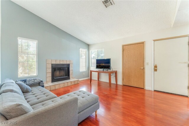2666 Aarondavid Dr, Las Vegas, NV 89121 - living area featuring lofted ceiling, wood finished floors, plenty of natural light, a tiled fireplace, and a textured ceiling