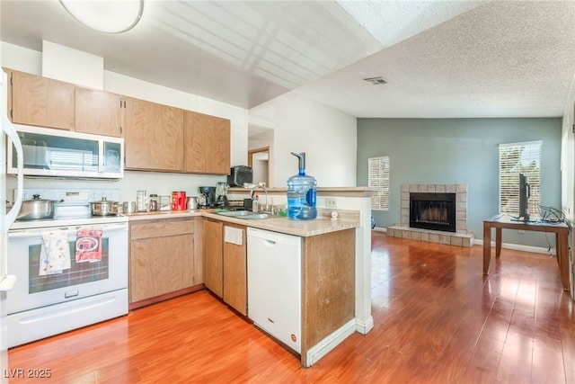 2666 Aarondavid Dr, Las Vegas, NV 89121 - kitchen with white appliances, a peninsula, light countertops, light wood-style floors, and open floor plan