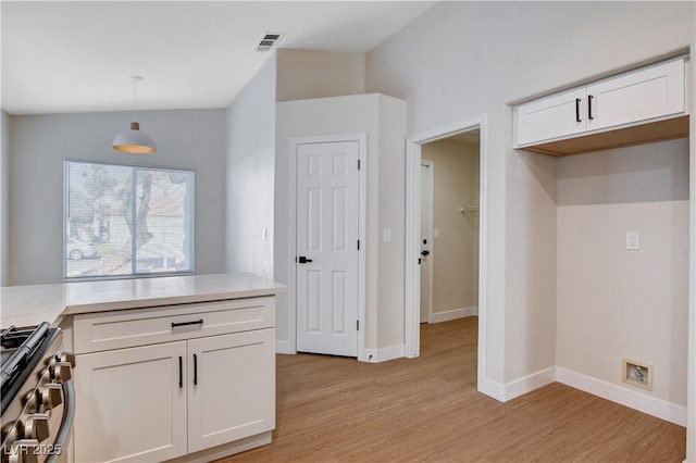 1005 Transom Dr, Las Vegas, NV 89128 - kitchen with stainless steel gas range oven, light wood-type flooring, white cabinetry, light countertops, and vaulted ceiling