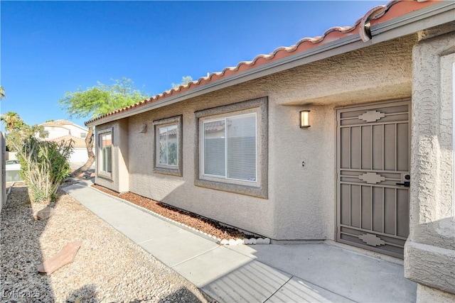 1005 Transom Dr, Las Vegas, NV 89128 - view of exterior entry featuring stucco siding, a patio, and a tiled roof