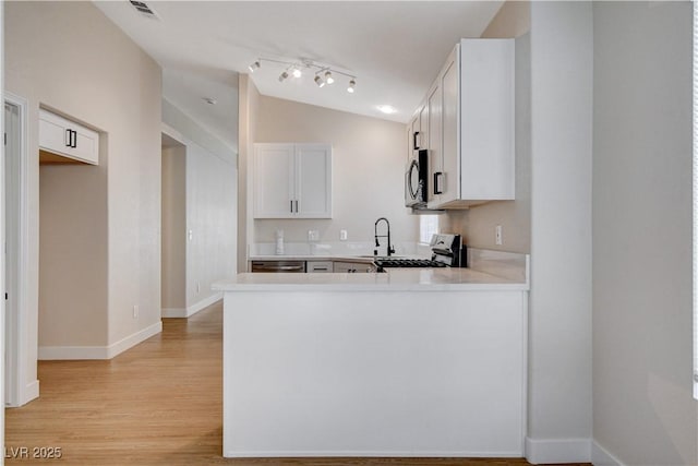 1005 Transom Dr, Las Vegas, NV 89128 - kitchen featuring stainless steel appliances, vaulted ceiling, light wood-style floors, light countertops, and a peninsula