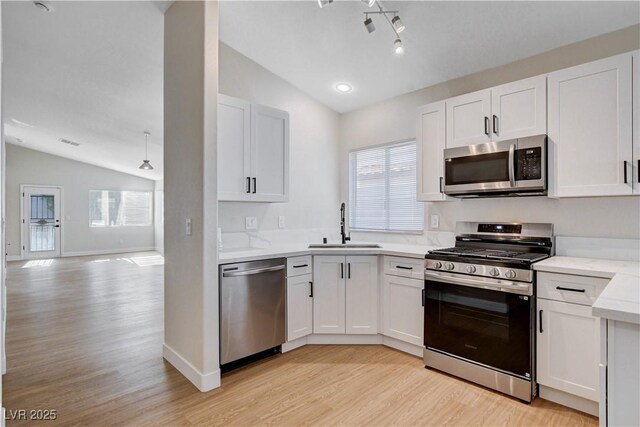 1005 Transom Dr, Las Vegas, NV 89128 - kitchen featuring stainless steel appliances, vaulted ceiling, light wood-style floors, and white cabinets