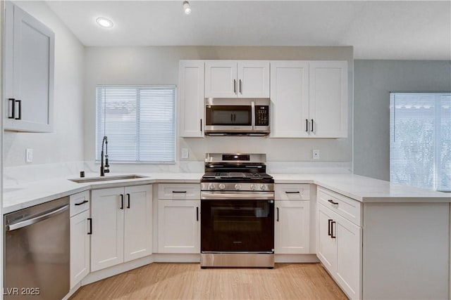 1005 Transom Dr, Las Vegas, NV 89128 - kitchen with stainless steel appliances, a peninsula, white cabinets, light wood-style floors, and recessed lighting